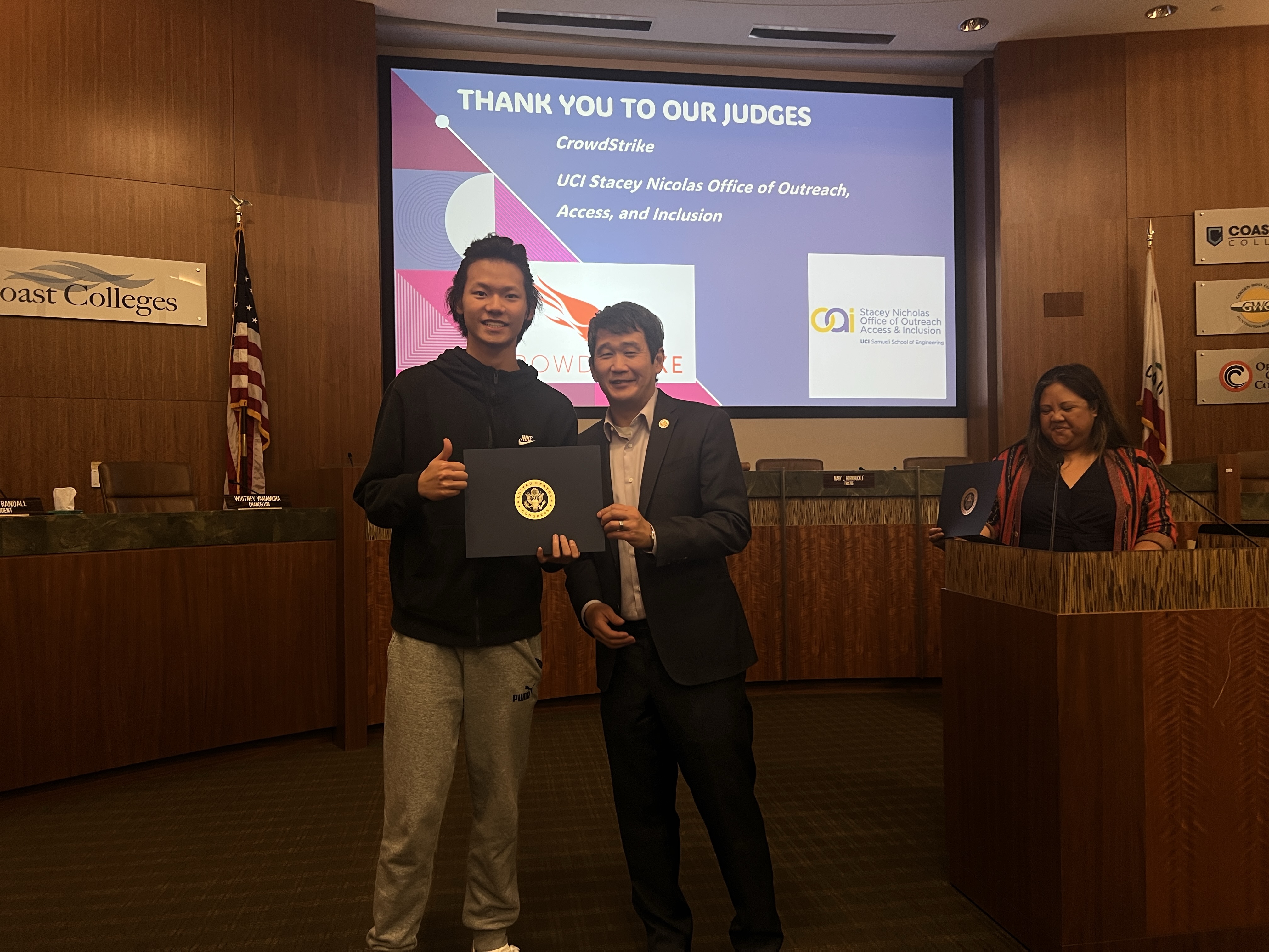 An award presentation with a student holding a recognition folder