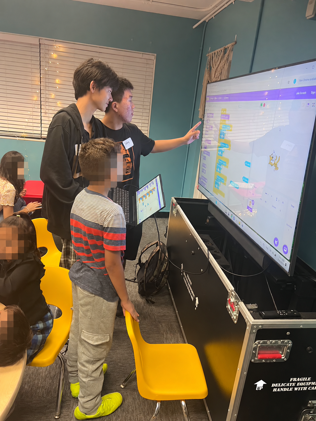 A group exploring Scratch programming on a classroom screen