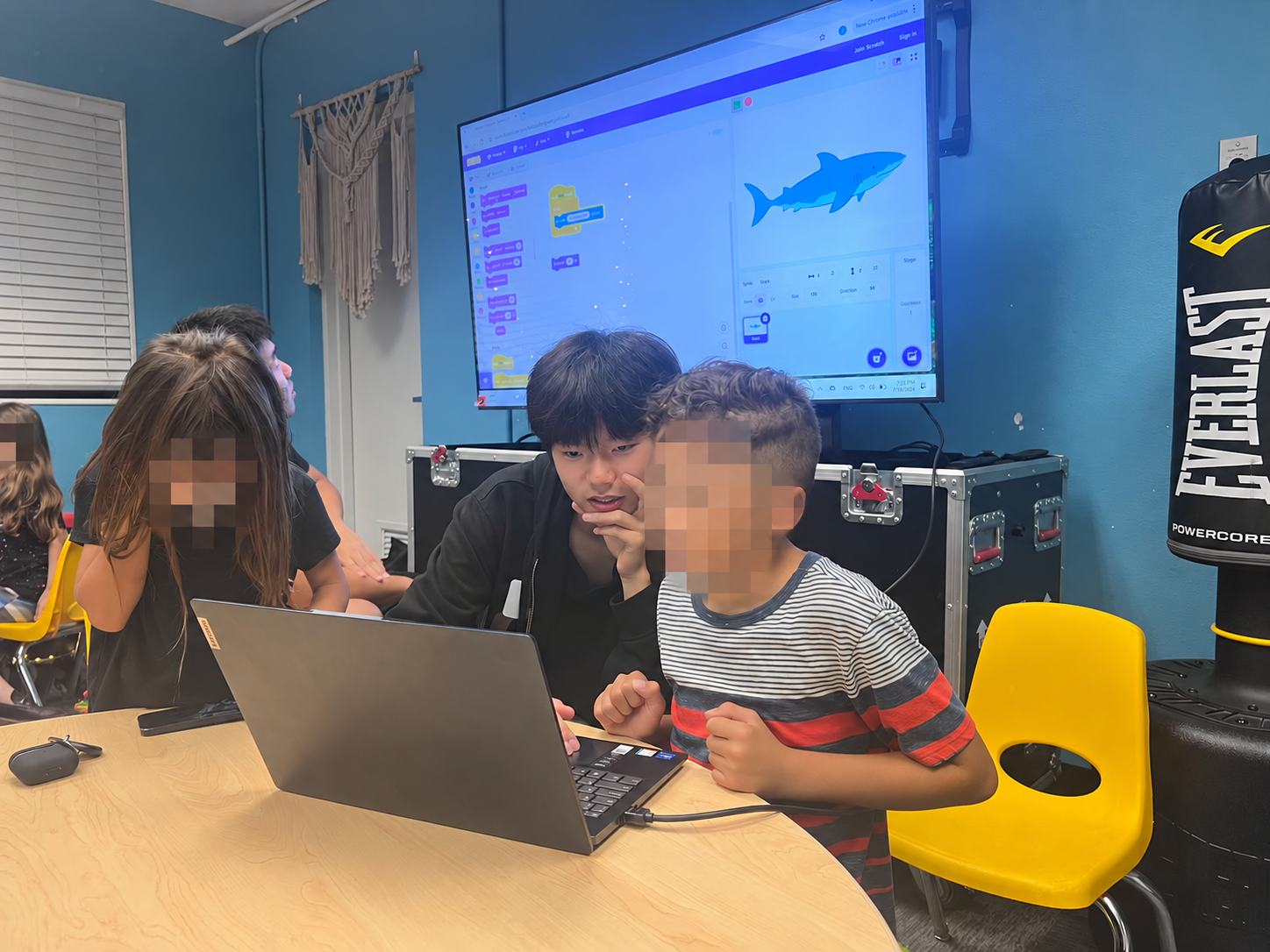 Children and a volunteer working together on a laptop